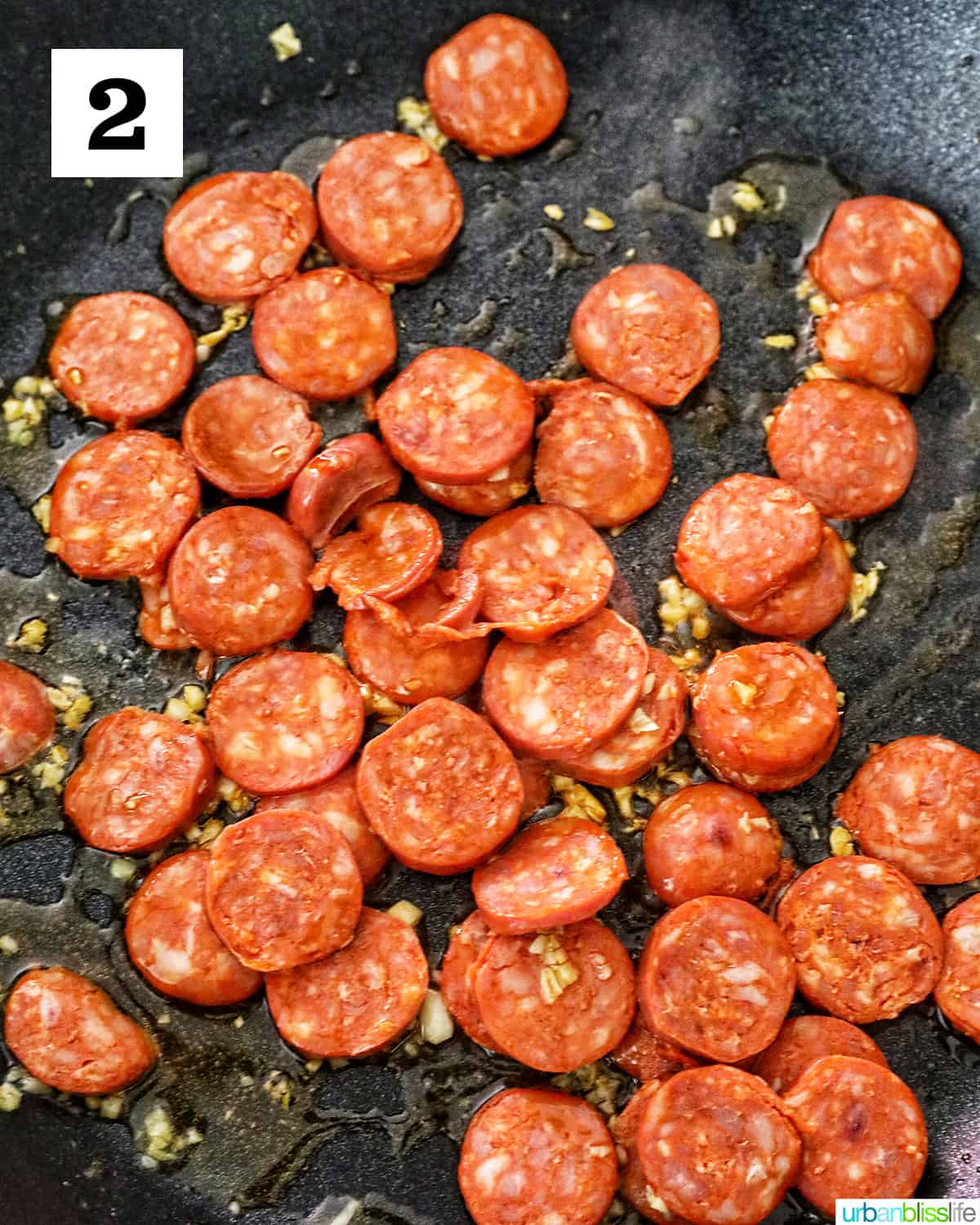 sliced linguica spanish meat cooking with garlic in a skillet.