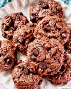 several chocolate cake mix cookies on a scalloped cream colored plate.