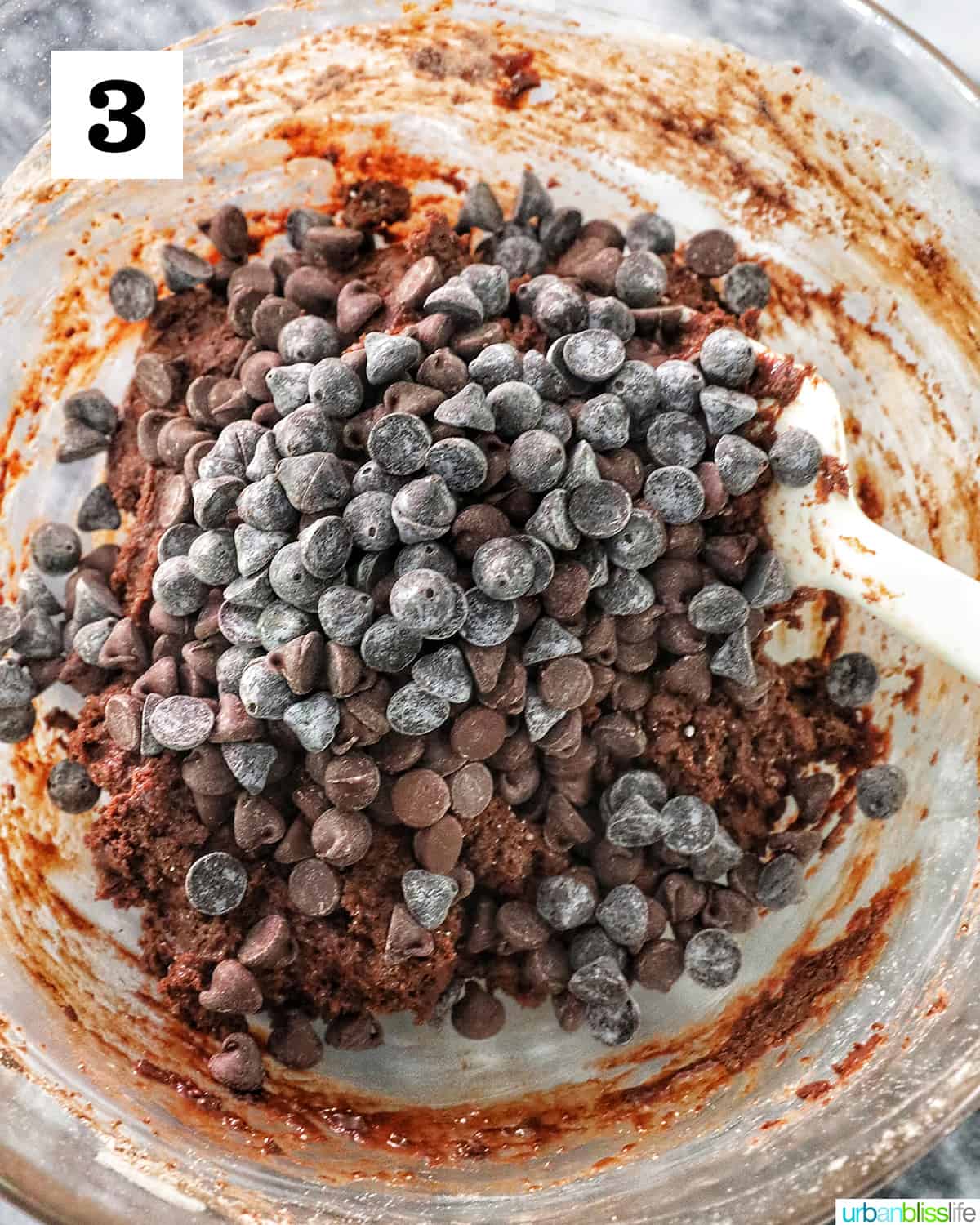 chocolate cake cookie mix topped with chocolate chips in a bowl with a spatula.