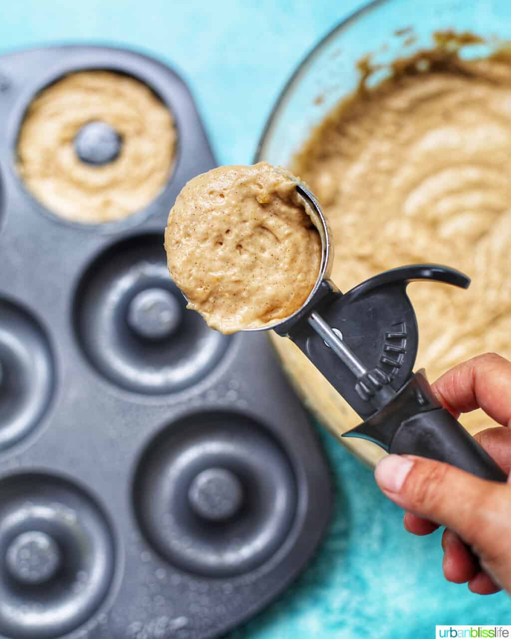 scooping apple cinnamon donut batter into donut pan