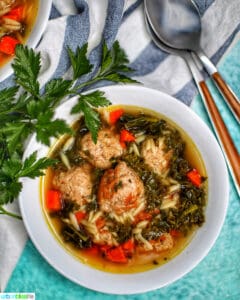 single white bowl of Italian Wedding Soup with two spoons
