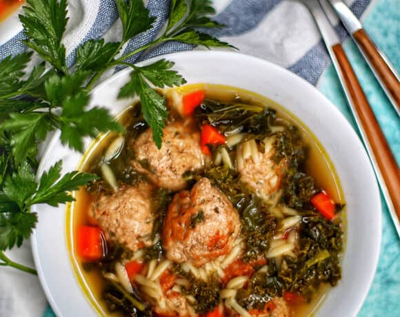 single white bowl of Italian Wedding Soup with two spoons