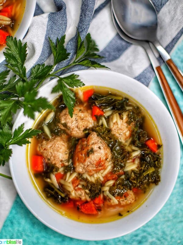 single white bowl of Italian Wedding Soup with two spoons