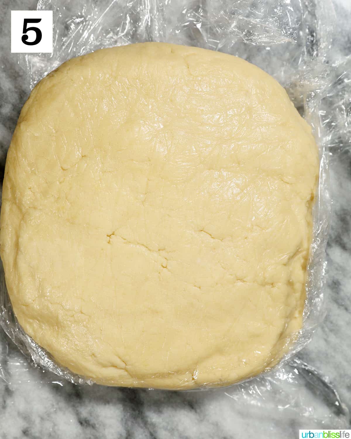 almond sugar cookie dough wrapped in plastic wrap to chill in the fridge.