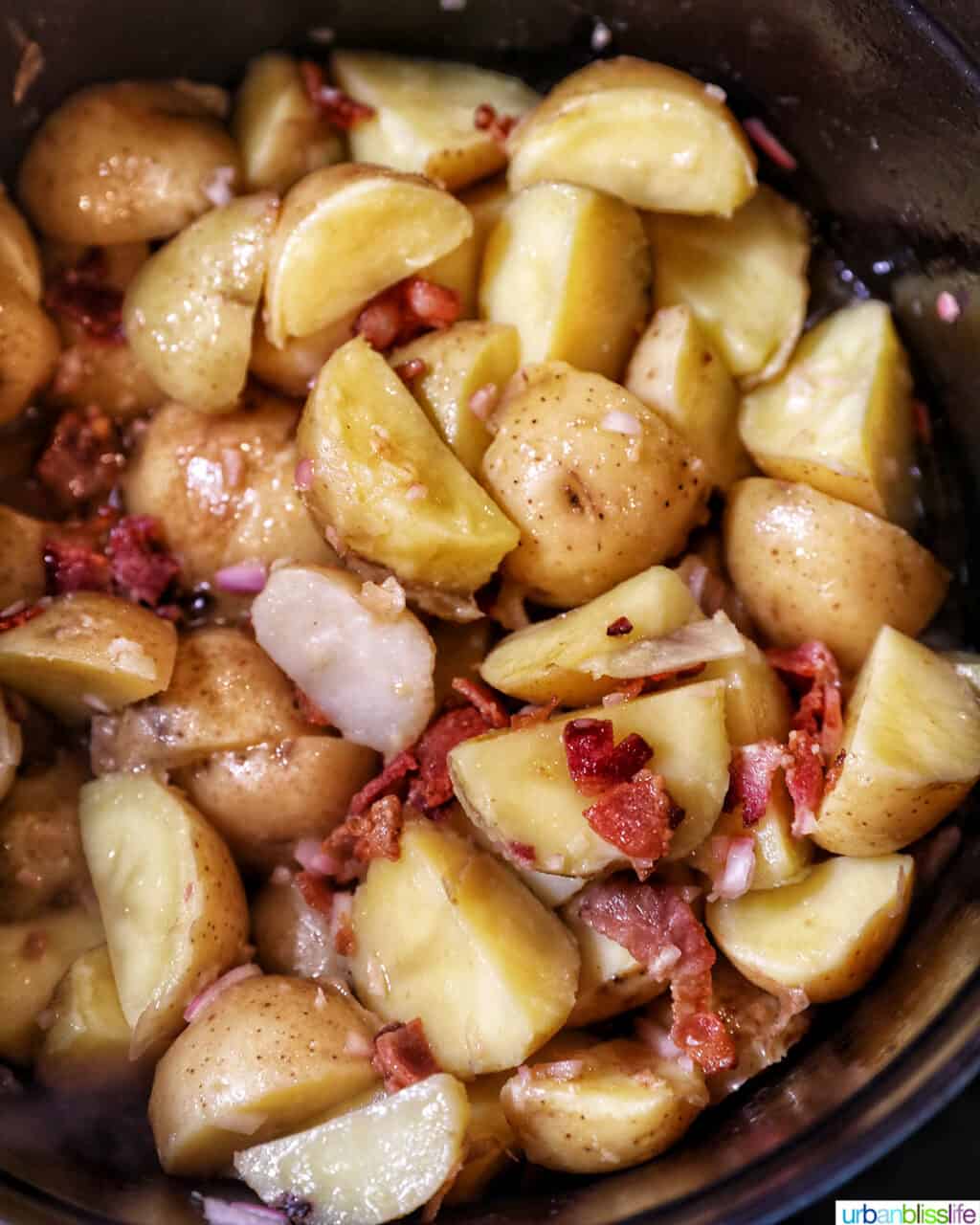 mixing baby potato salad with bacon