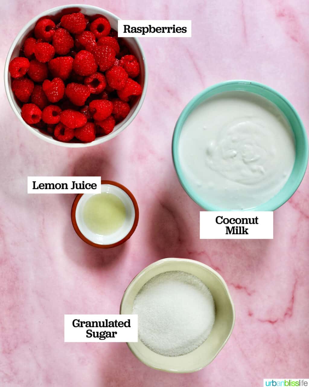 bowls with ingredients to make raspberry sherbet, on top of a pink table.