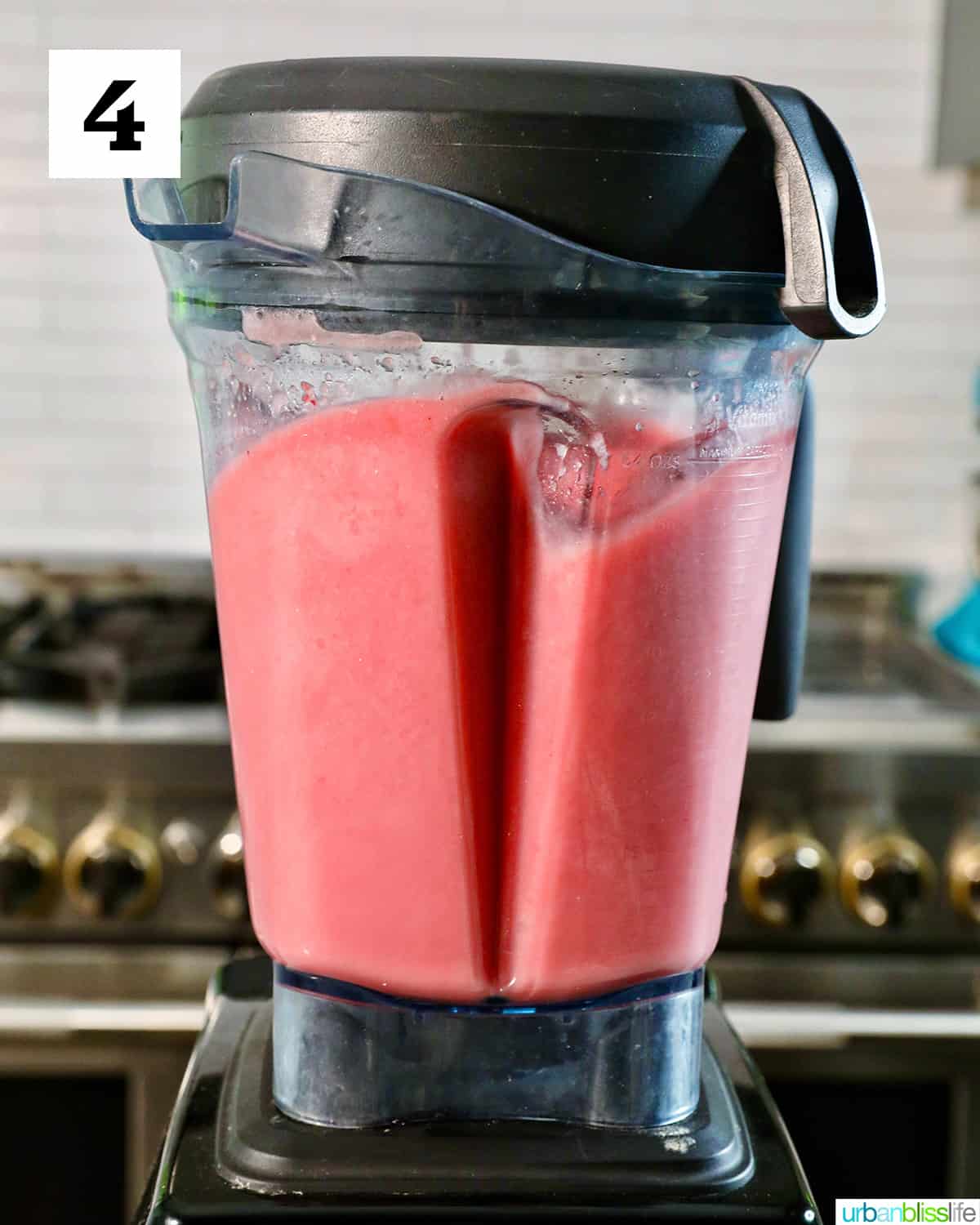 strawberry watermelon smoothies blended in a blender with stove in background.