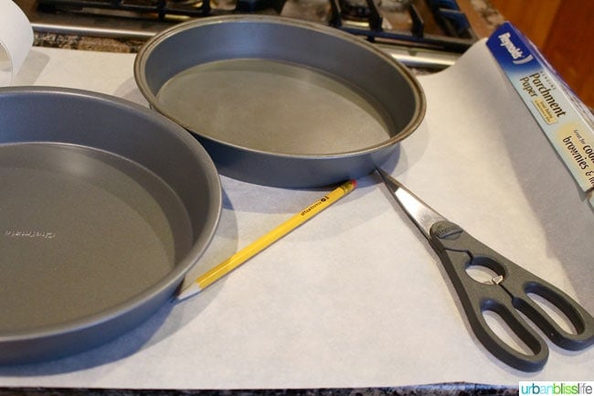 two cake pans with scissors, pencil, and parchment paper.