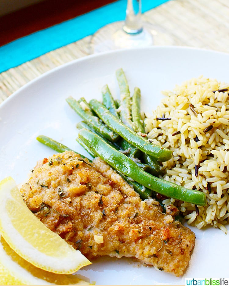 Pan fried cod with side of green beans, rice, and lemon wedge.