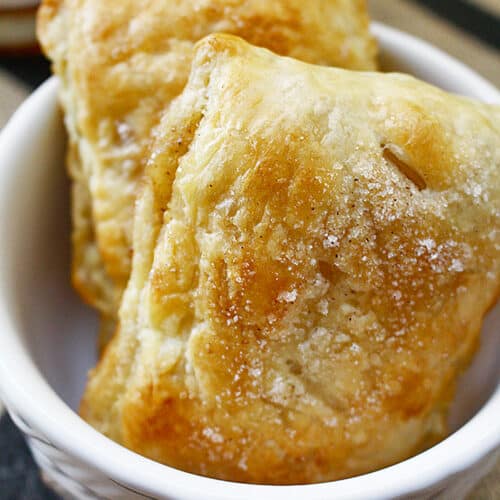 two apple whiskey hand pies in a white bowl.