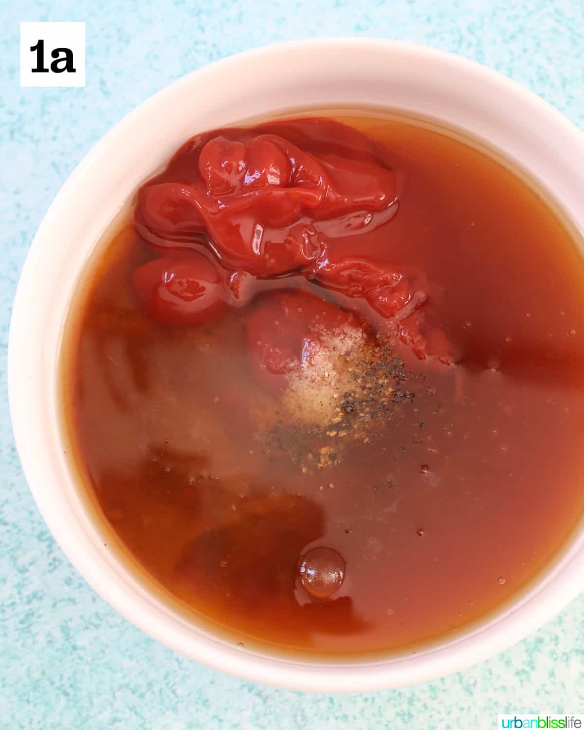 white bowl with ingredients to make the sauce for slow cooker honey bourbon meatballs on a blue background.