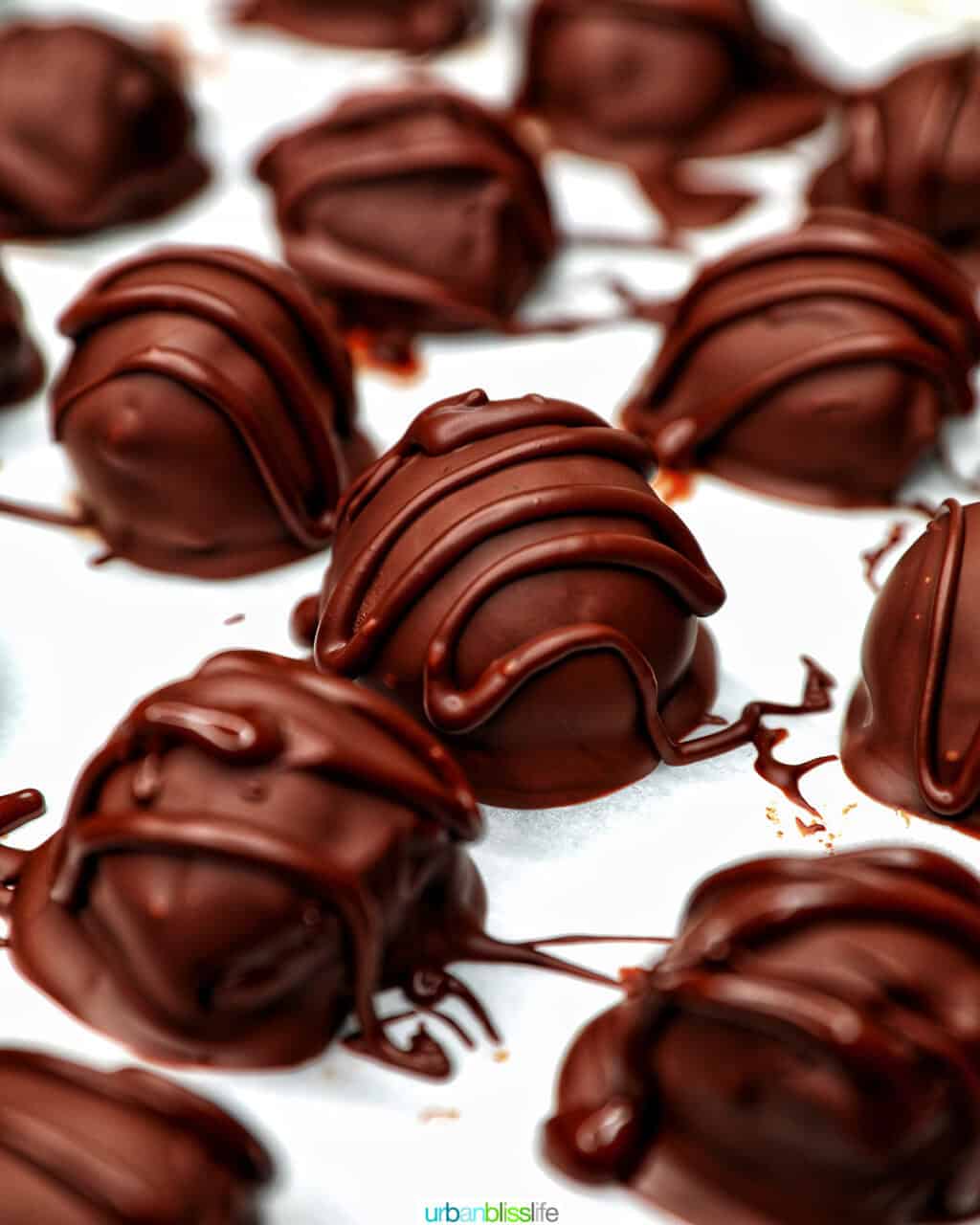 chocolate coating being drizzled onto honey bourbon truffles.