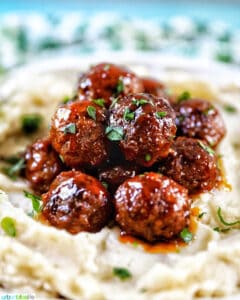 side view of slow cooker honey bourbon meatballs on a bed of mashed potatoes.