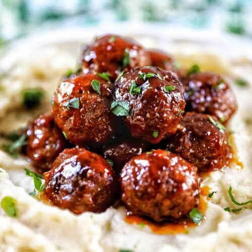 side view of slow cooker honey bourbon meatballs on a bed of mashed potatoes.