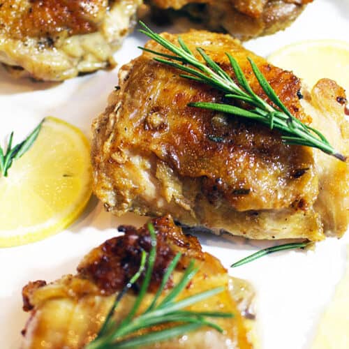 cast iron skillet chicken with rosemary sprig and lemon slices.