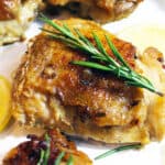 cast iron skillet chicken with rosemary sprig and lemon slices.