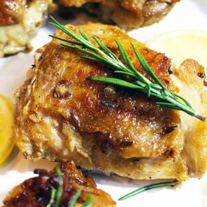cast iron skillet chicken with rosemary sprig and lemon slices.