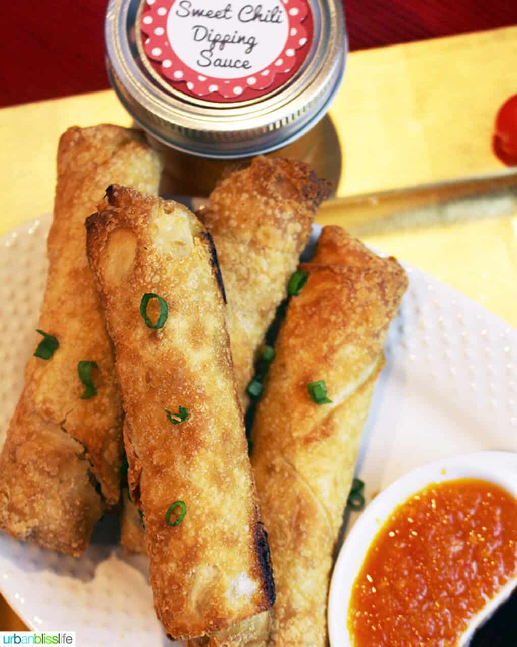 sweet chili dipping sauce in a bowl surrounded by egg rolls.