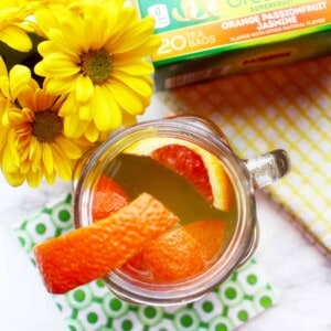 orange slices in a tea cup with yellow flowers and package of tea.