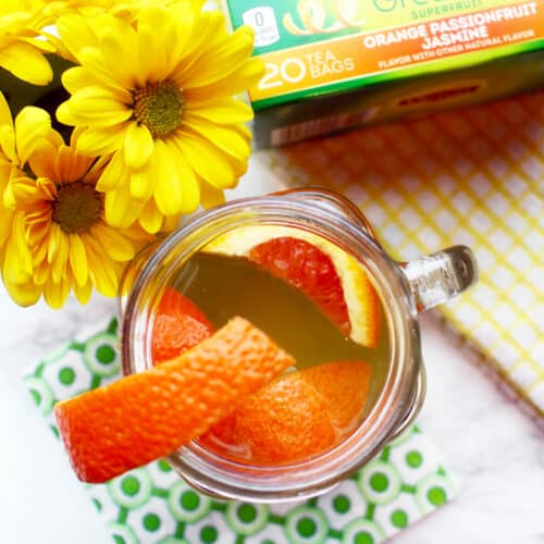 orange slices in a tea cup with yellow flowers and package of tea.
