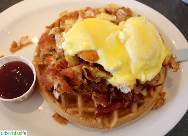 white plate with chicken and waffles with poached eggs at Floyd's Diner in Victoria British Columbia, Canada.