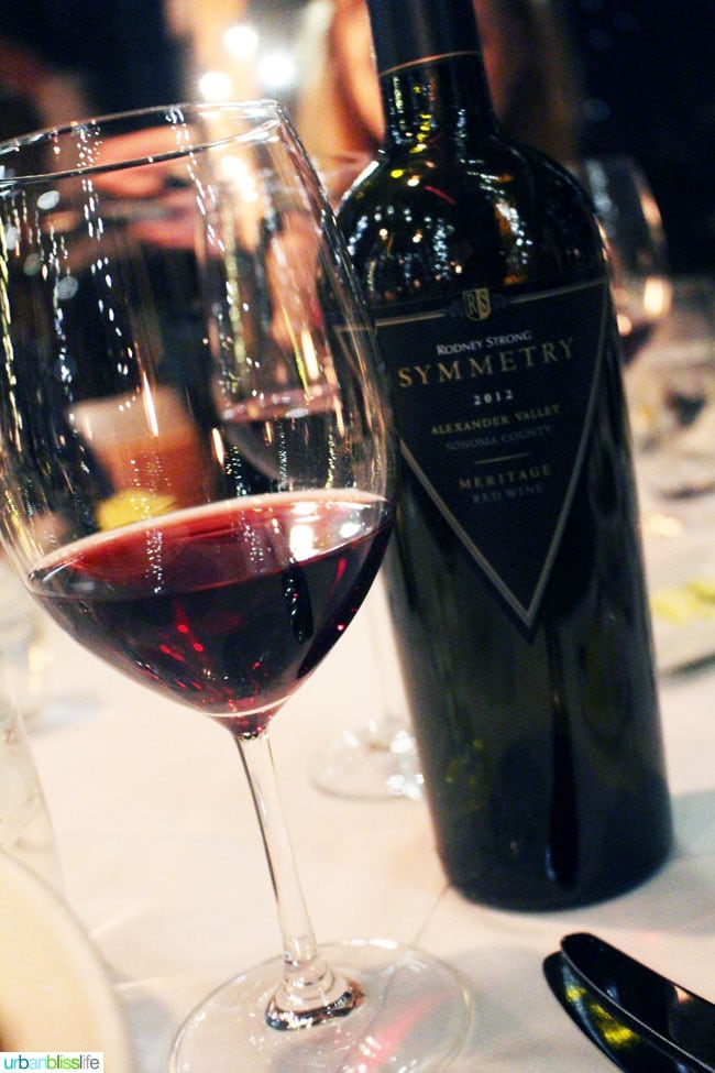 glass of red wine with Rodney Strong bottle of wine on white tablecloth.