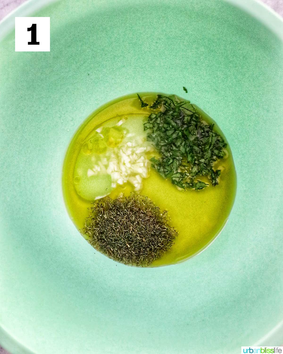 green bowl with oil, garlic, and herbs to marinate shrimp.
