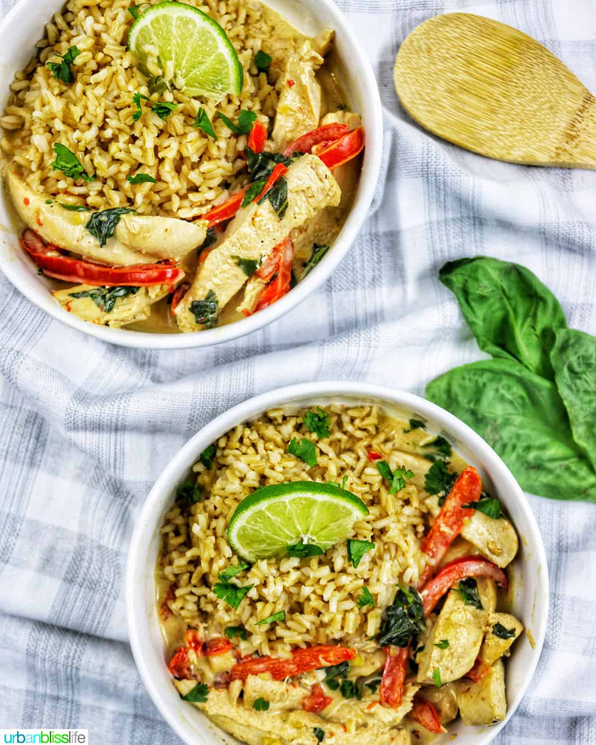 two bowls of Thai coconut lime chicken with red bell pepper slices and lime slices over rice.