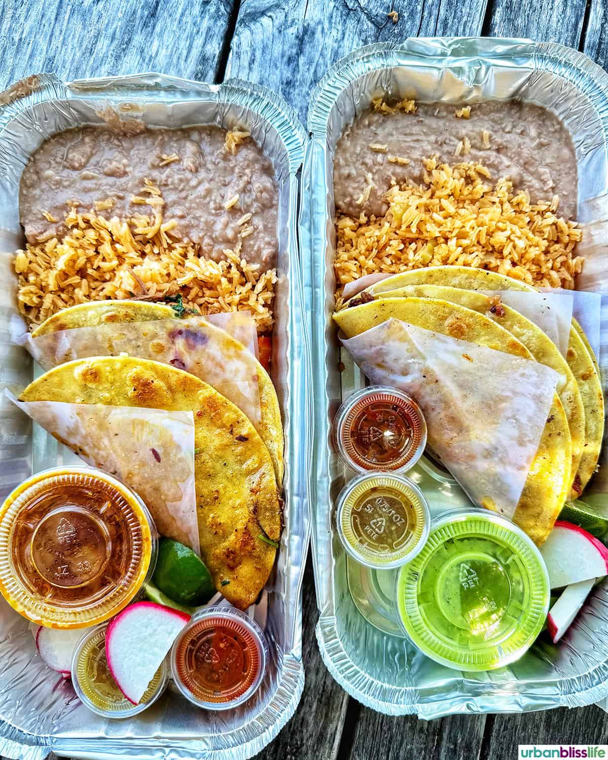 two plates of tacos with rice and beans.
