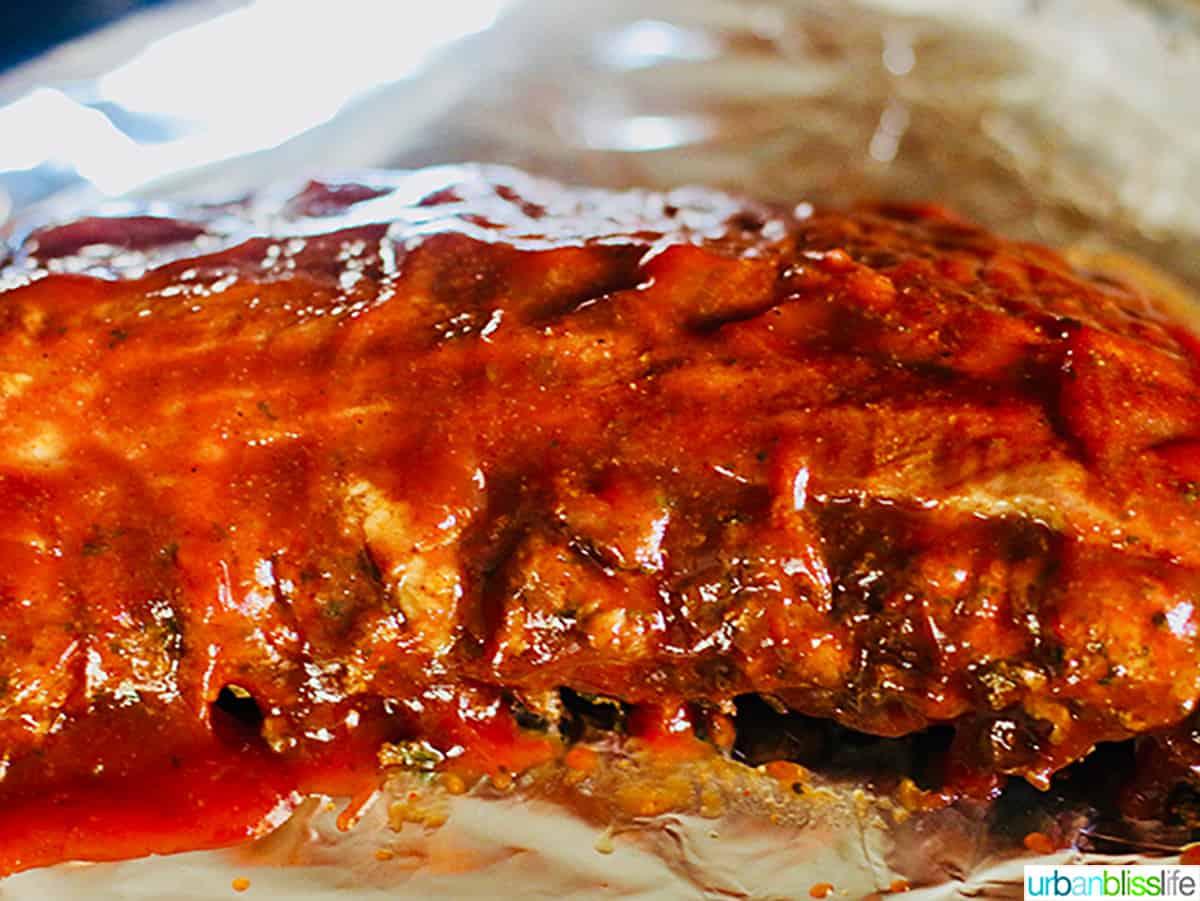 pork ribs with BBQ sauce slathered on top, on foil.