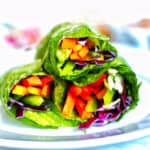 three rainbow salad rolls stacked on a plate.