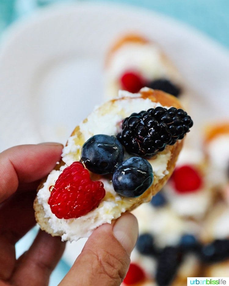 holding a single summer berry crostini