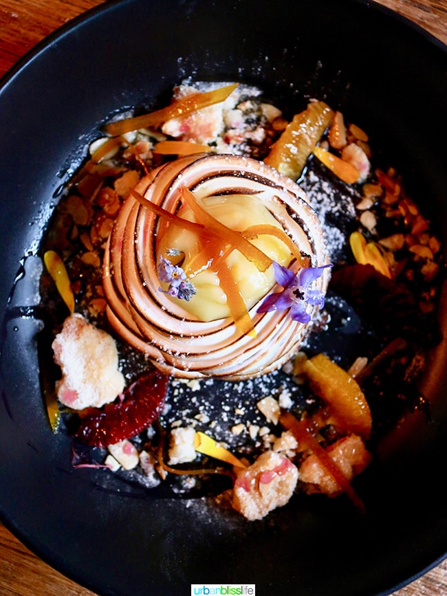 lemon curd dessert with colorful edible flowers in a black bowl at The Bewildered Pig restaurant 