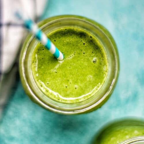 closeup looking into a mason jar with super green smoothie on a blue background