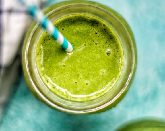 closeup looking into a mason jar with super green smoothie on a blue background