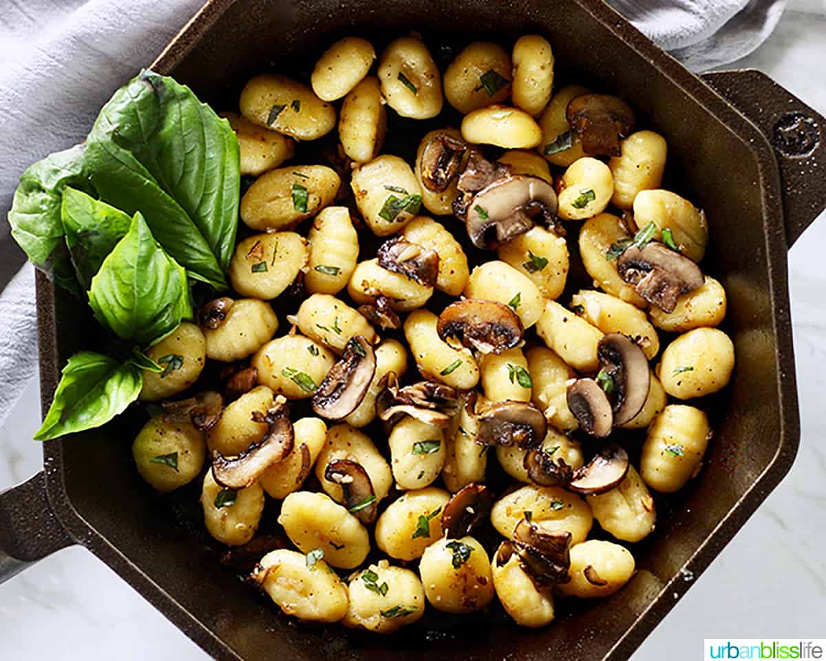 cast iron skillet with gnocchi, mushrooms, basil.