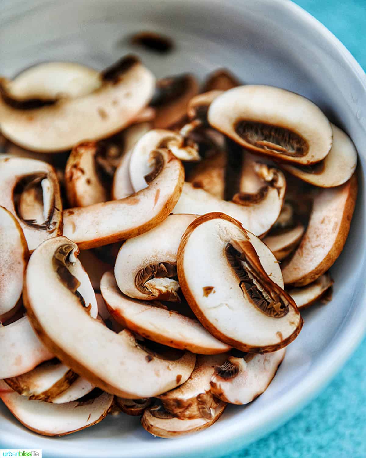 white bowl with sliced mushrooms.