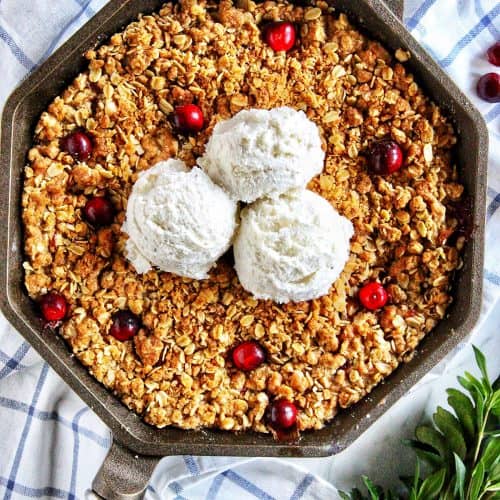 skillet apple cranberry crisp with three scoops of vanilla ice cream
