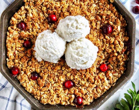skillet apple cranberry crisp with three scoops of vanilla ice cream