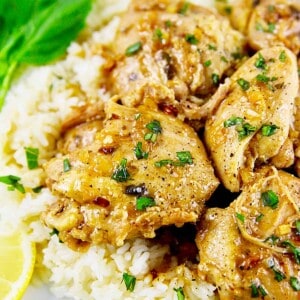 instant pot lemon garlic chicken over rice with side of lemon slice and herbs.