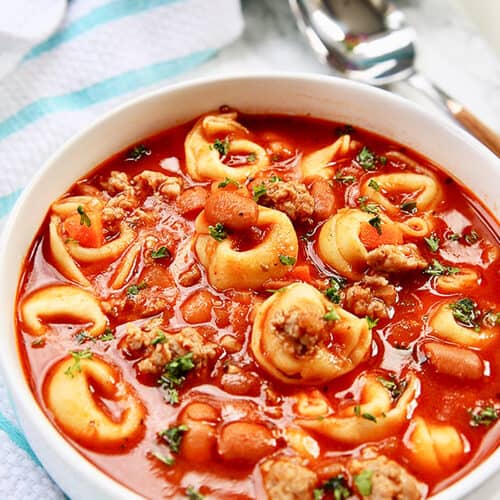 bowl of sausage tortellini soup with spoon on side