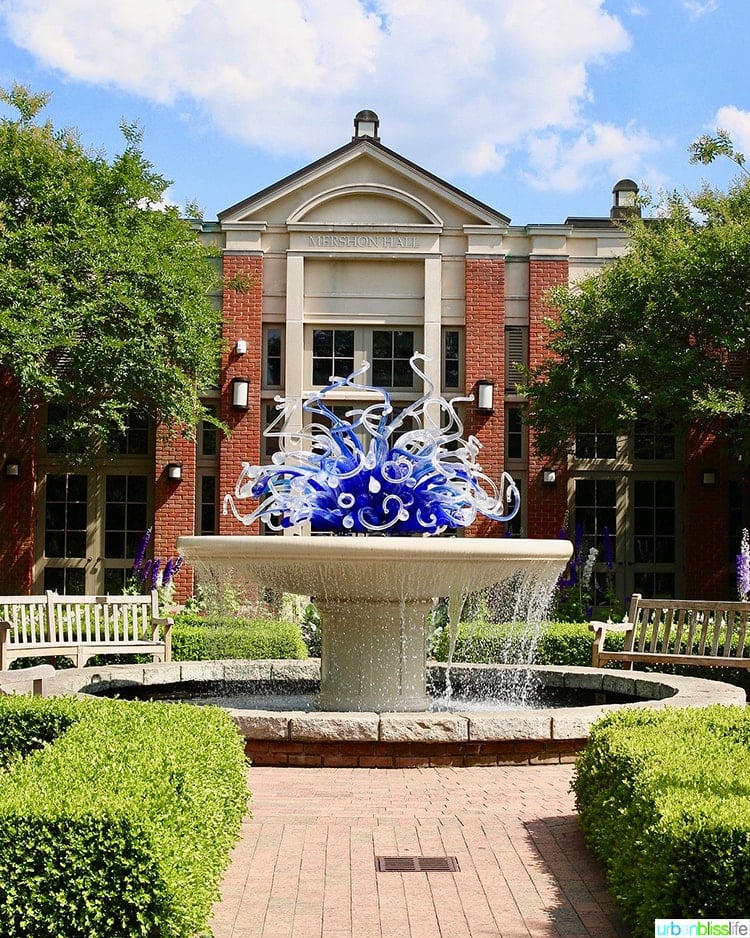 chihuly purple glass sculpture in  water fountain in front of a building.