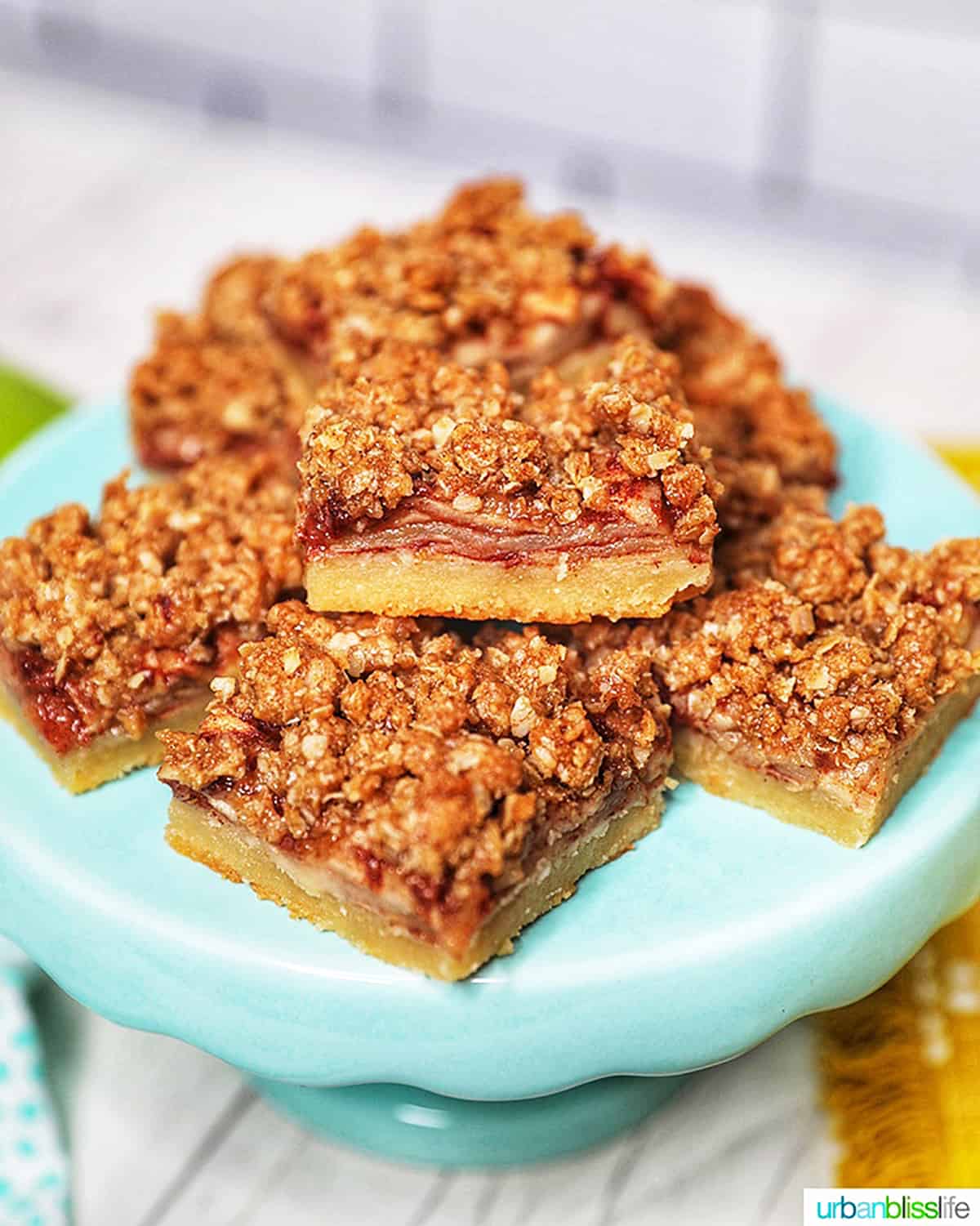 stack of apple pie bars on a blue cake pedestal.