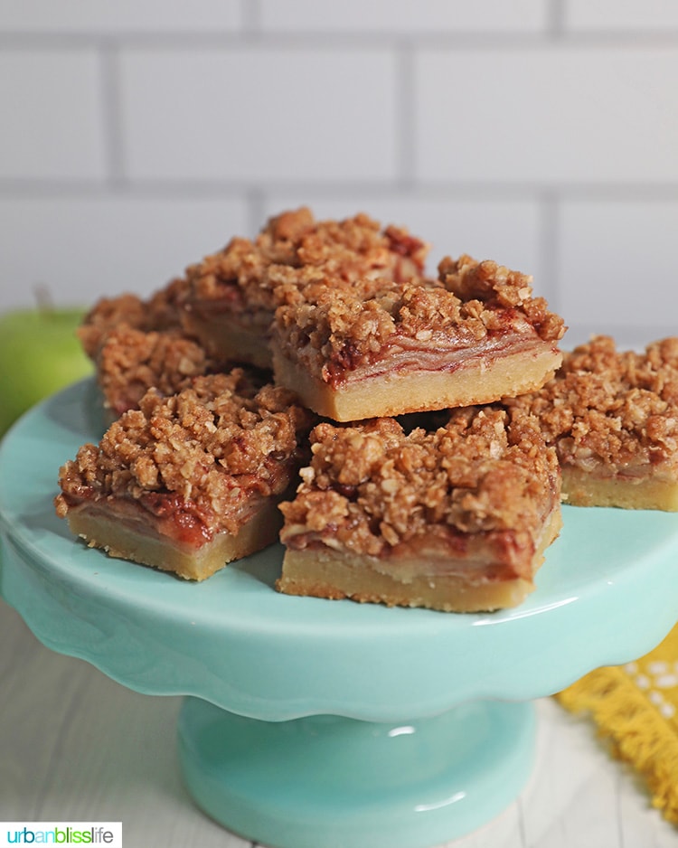 stacks of apple pie bars on an aqua blue cake pedestal.