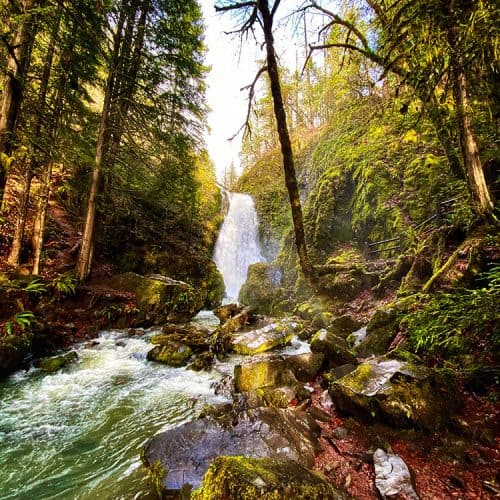 sun peeking out over Susan Creek Falls waterfall