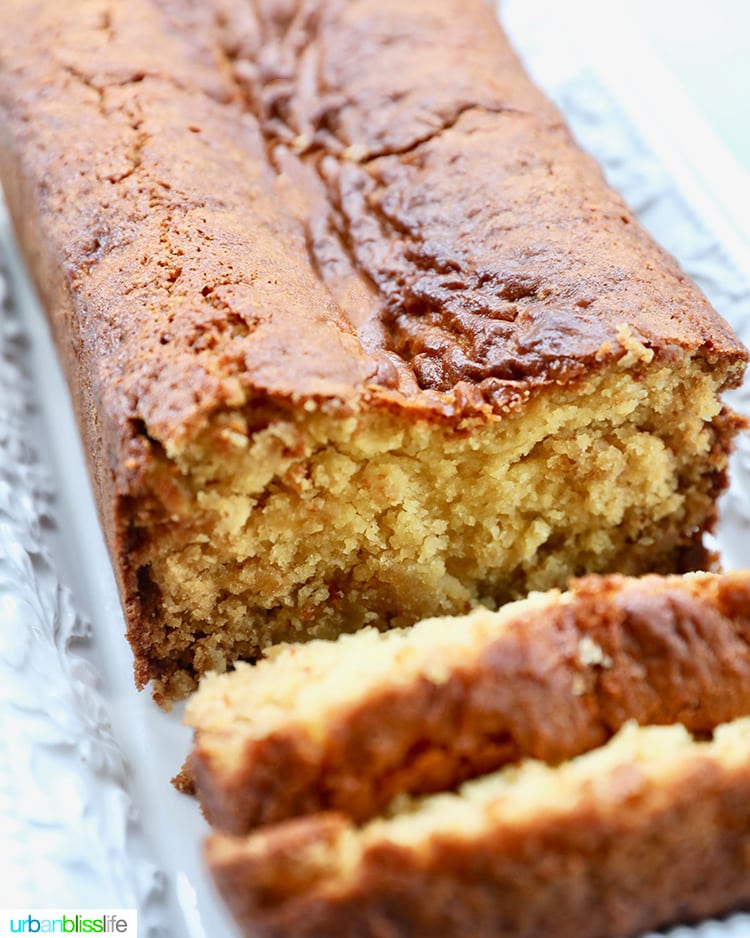 loaf of pineapple bread sliced with one slice laying flat, on a white serving platter.