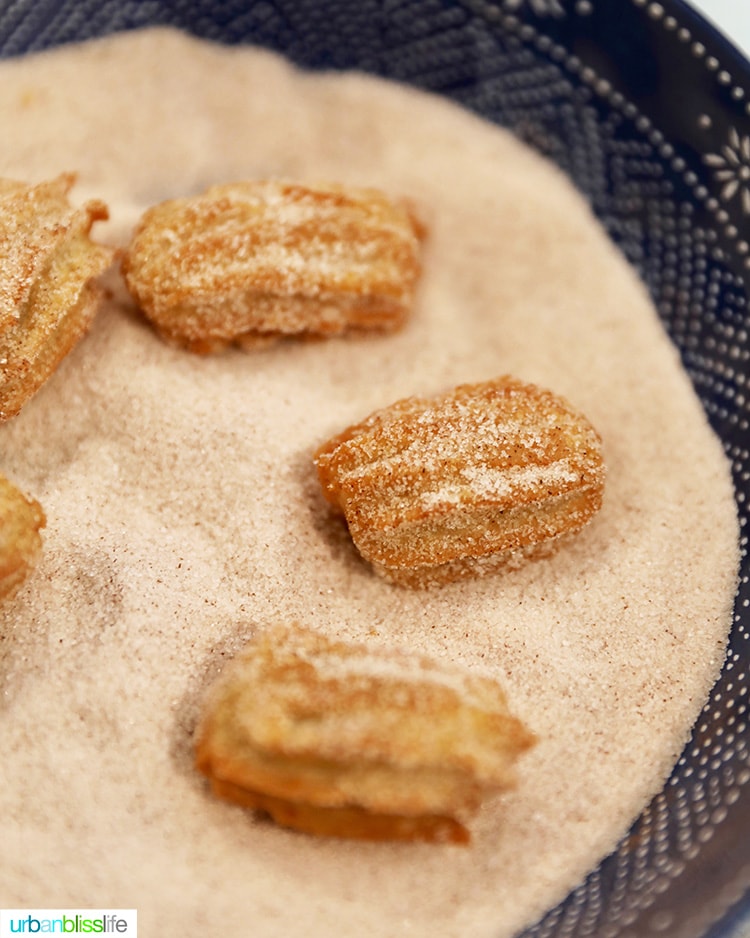 coating churros with cinnamon sugar