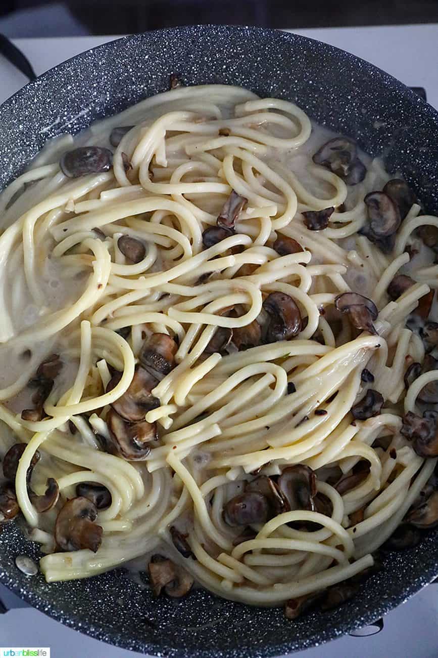adding cream to pasta and mushrooms