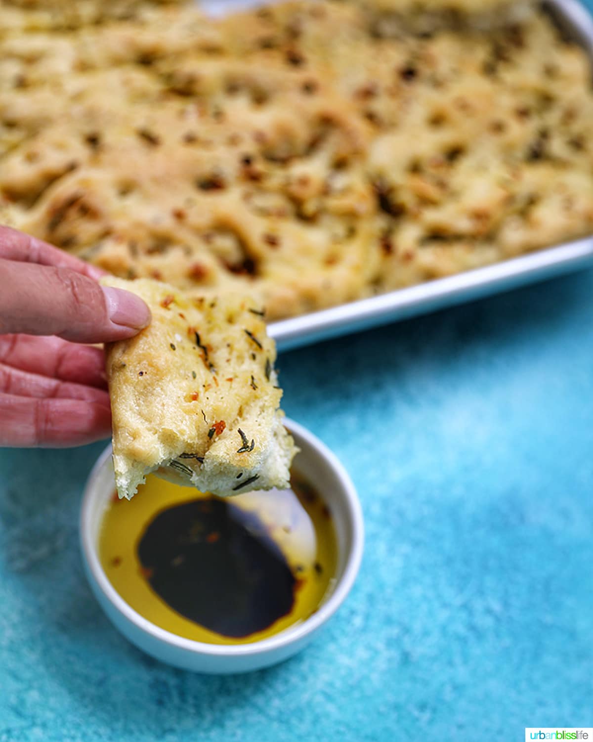 slice of focaccia bread dipping into balsamic vinegar
