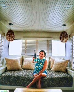 Marlynn Schotland holding up a bottle of wine inside the mansion airstream at Vintages Trailer Resort